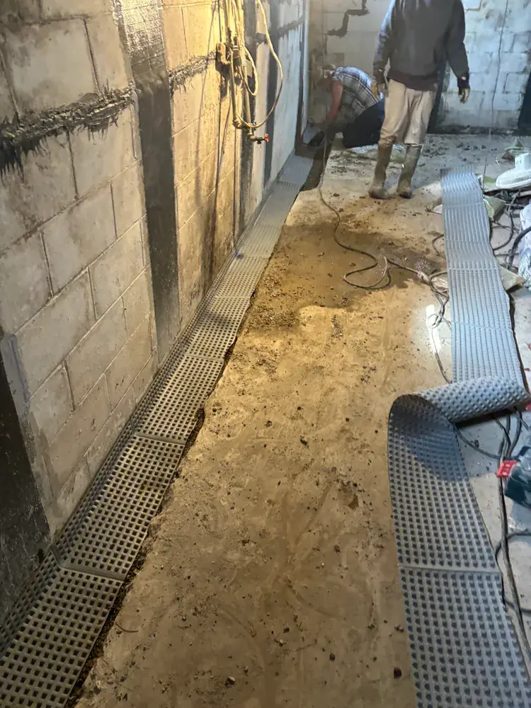 Drain track being installed along a block basement wall