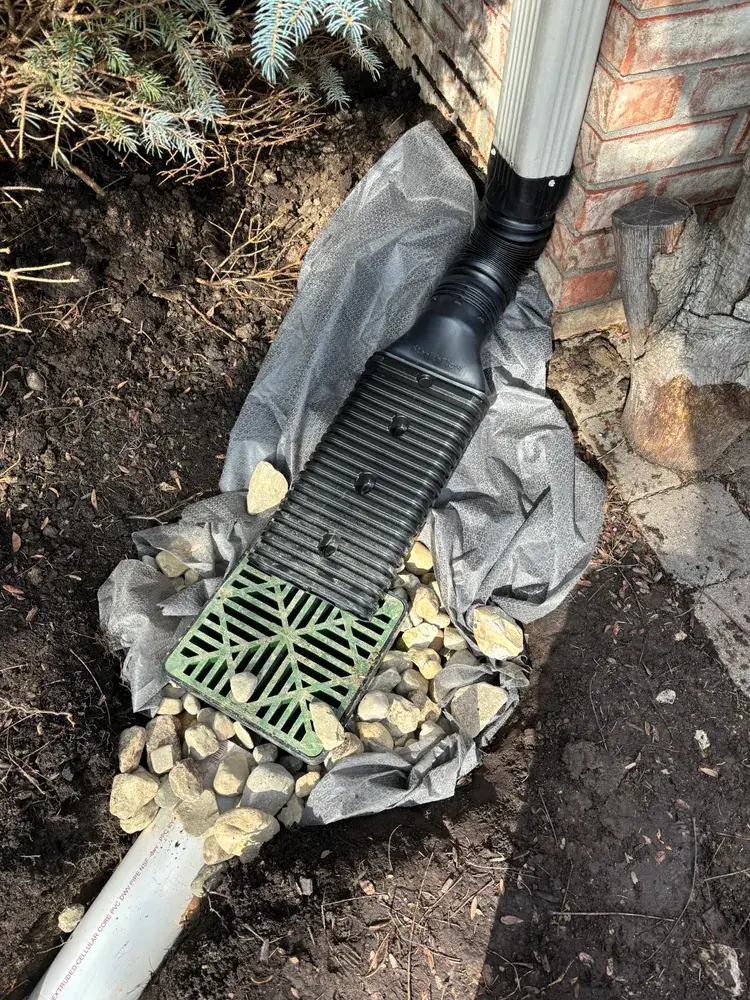 Downspout draining into a buried catch basin lined with filter fabric