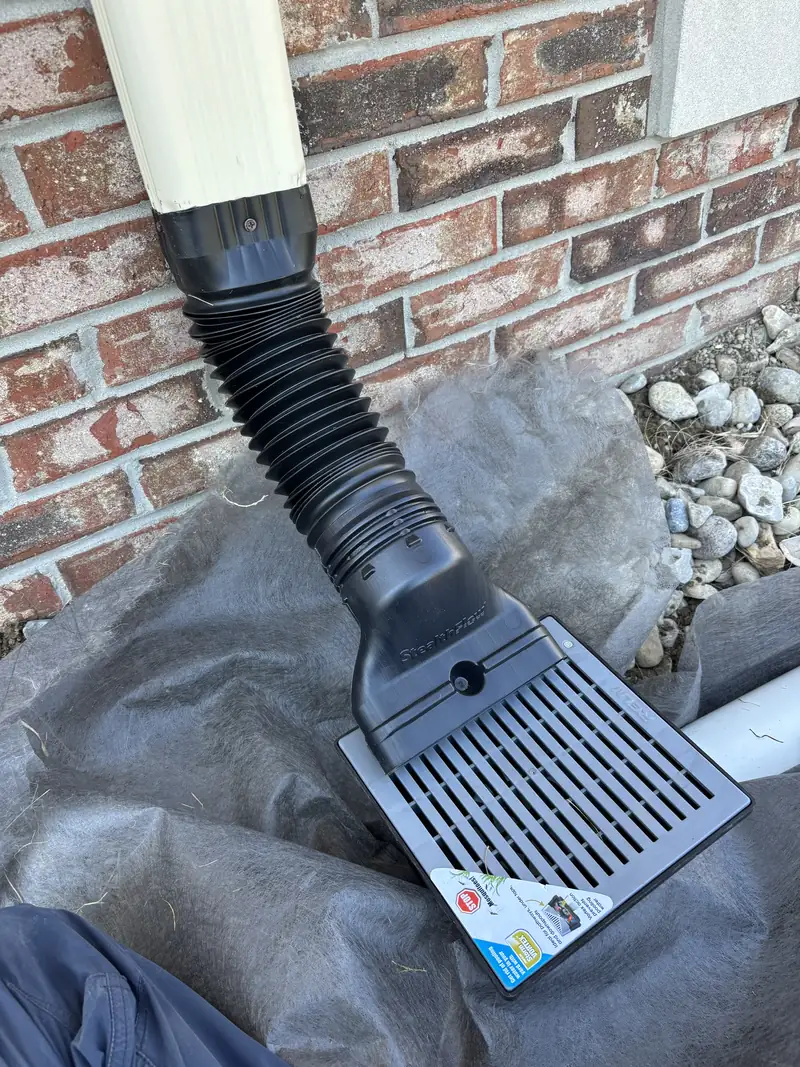 Grate being installed under a downspout as part of a buried drain line