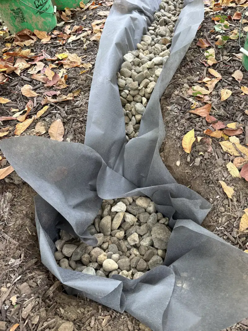 Before: the dry well hole lined with fabric and filled with rock, with the trench drain running into it