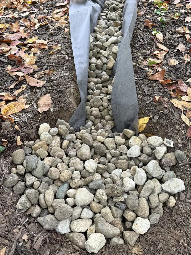 After: river rock spread over the wrapped dry well where the trench drain ends