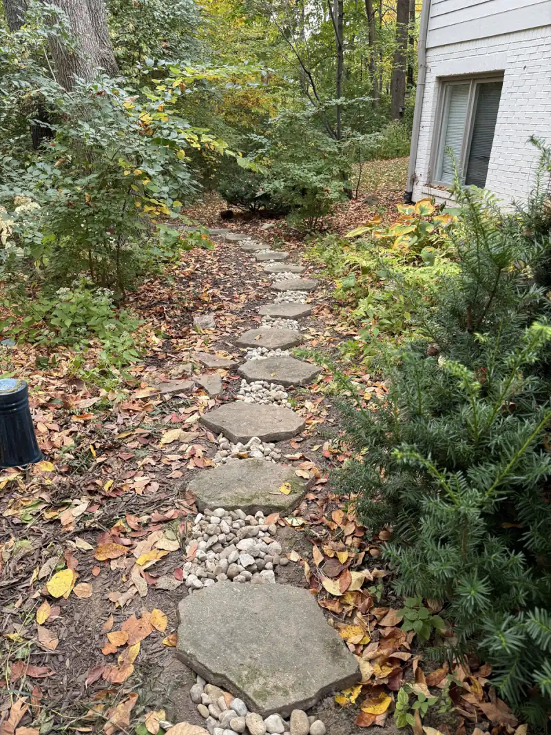 Stepping-stone path beside a house with river rock showing between the stones