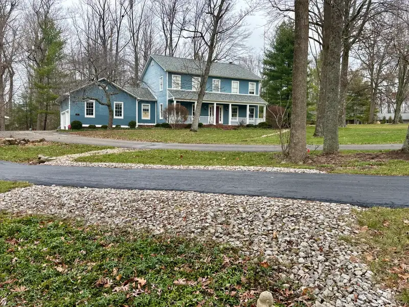 Trench drain covered in stone, running away from the house to the far side of a driveway