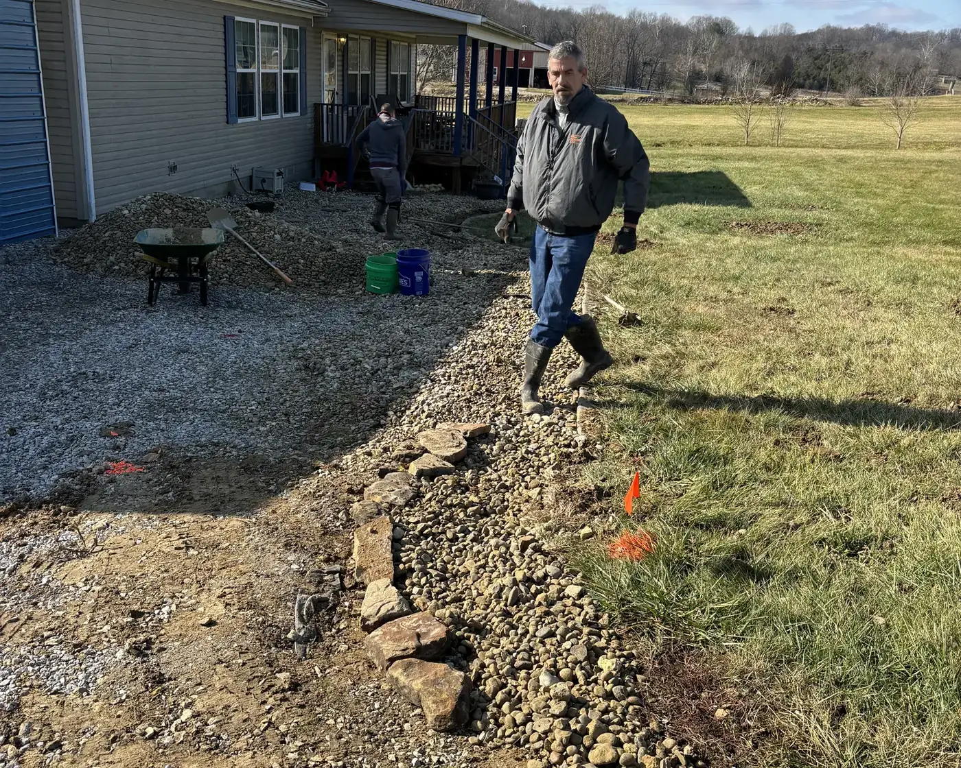 Anthony Piatt walking a freshly cut drainage line along the side of a rural Indiana home