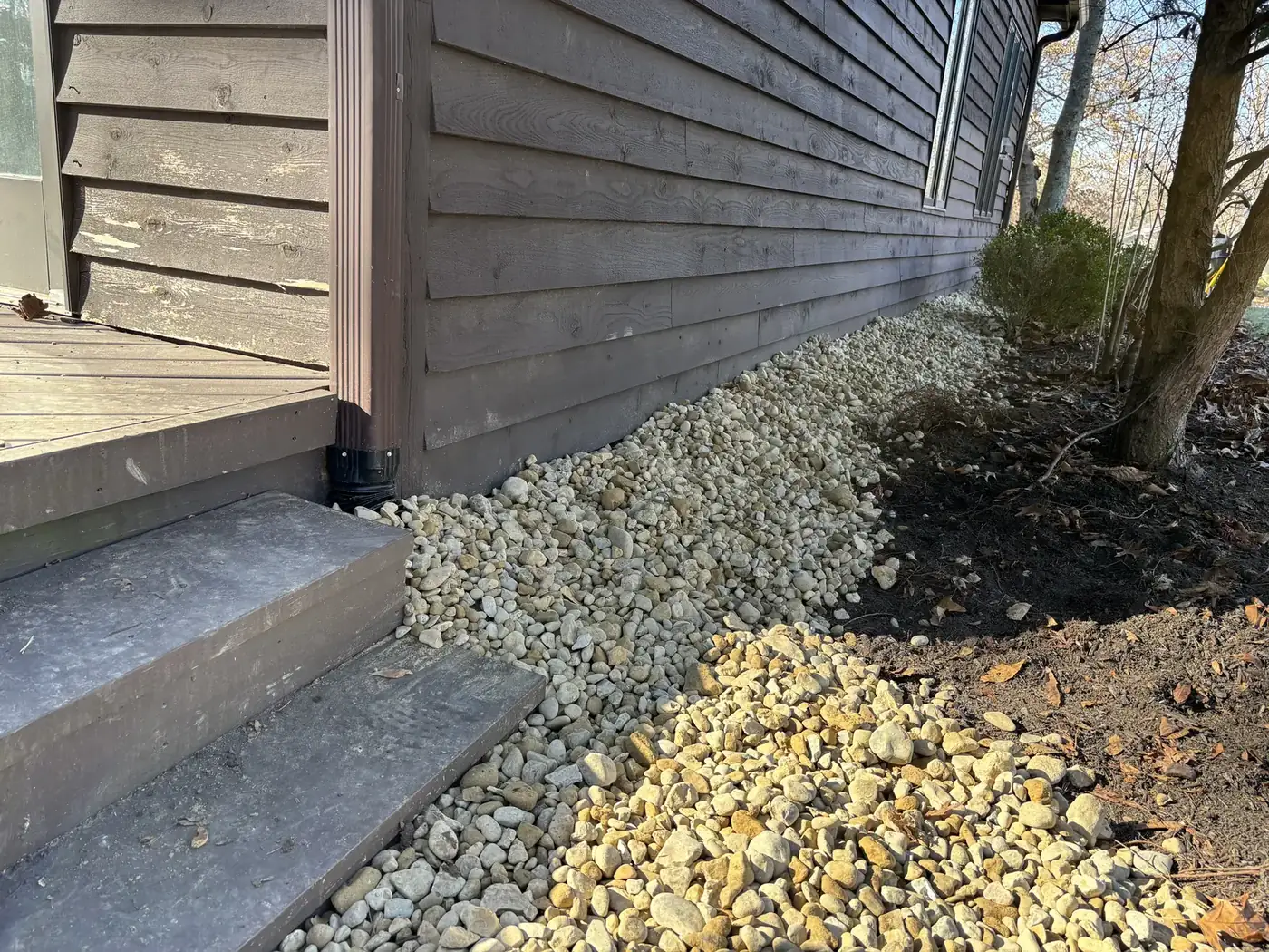 A rock-filled drainage strip laid through the narrow side yard between two Fishers homes