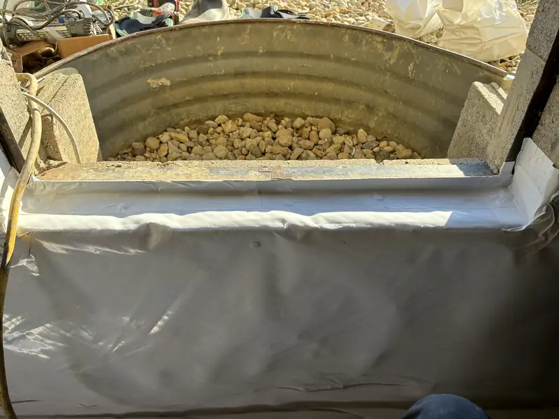 Round metal liner filled with stone and wrapped in white barrier