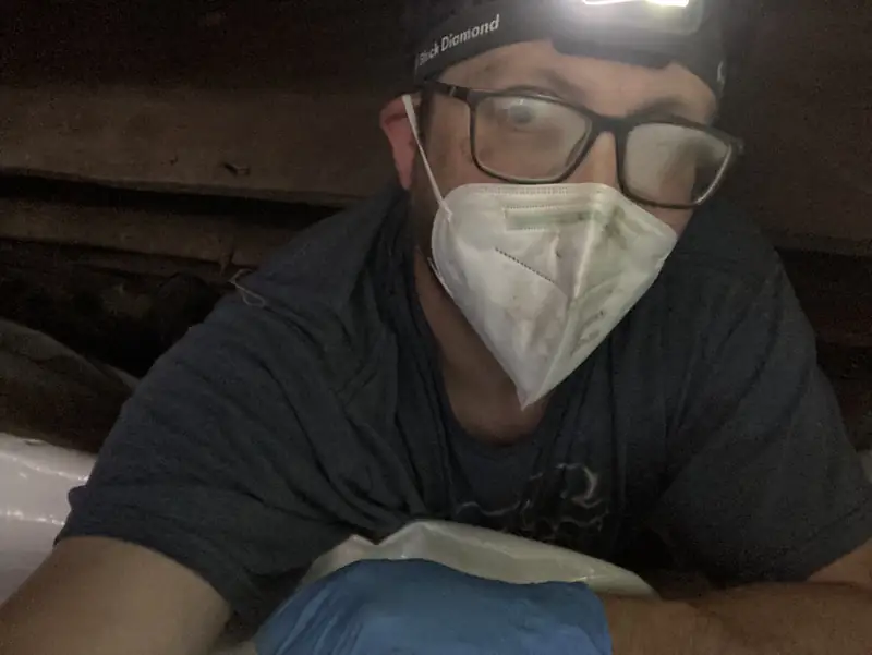 Technician in a mask inside a crawlspace