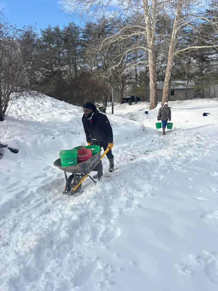 Hoosier Water Away crew moving wheelbarrows of stone across a snow-covered yard